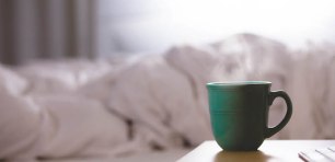 Coffee cup next to a bed doona days sick leave