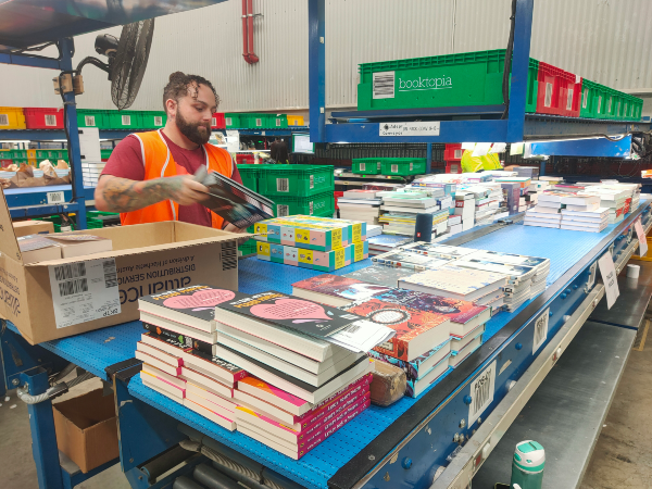 Booktopia worker unpacking books in warehouse