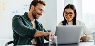 Two business people using a laptop together in an office