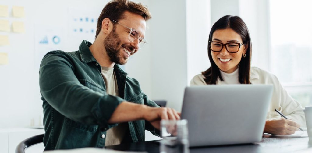 Two business people using a laptop together in an office