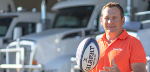 Truckit founder Robert Russel standing in front of trucks bouncing rugy ball