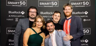 Untitled Group marketing team poses in front of Smart50 media wall